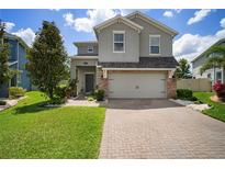 Charming two-story home featuring a gray exterior, brick accents, and a well-manicured front yard at 19278 Roseate Dr, Lutz, FL 33558