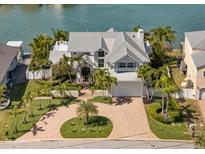 Beautiful waterfront home featuring lush landscaping, a circular driveway, and a spacious garage at 213 Harrison Ave, Belleair Beach, FL 33786