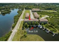 An aerial view of waterfront condos featuring boat lifts and lush, green surroundings at 6533 Channelside Dr, New Port Richey, FL 34652
