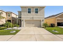 Beige home exterior featuring a spacious driveway and a two-car garage at 10230 Geese Trail Cir, Sun City Center, FL 33573