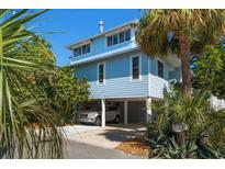 Charming stilt home with beachy blue siding, lush landscaping, and convenient covered parking at 118 94Th Ave, Treasure Island, FL 33706