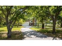 Beautiful exterior view of home showing the driveway leading up to the garage surrounded by mature trees at 1691 Ridge Top Dr, Tarpon Springs, FL 34688