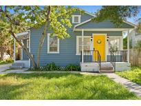 Charming home featuring a cheerful yellow front door and well-maintained lawn at 2215 Thrace St, Tampa, FL 33605