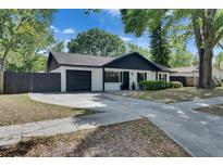 Charming single-story home with a well-manicured lawn, a black roof, and an attached garage at 2420 Forrest Crest Cir, Lutz, FL 33549