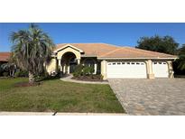 Charming single-story home featuring a tile roof, arched entryway, well-manicured lawn, and three-car garage at 2679 Saddlewood Ln, Palm Harbor, FL 34685