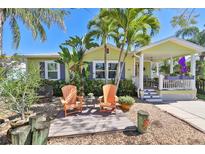 Charming home with lush landscaping, covered porch, and an inviting outdoor seating area with Adirondack chairs at 3008 Dupont S St, Gulfport, FL 33707