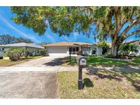 Charming single-story home with a well-manicured lawn and mature shade trees in a quiet neighborhood at 3957 Tarpon Pointe Cir, Palm Harbor, FL 34684