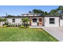 Charming single-story home featuring an orange front door, manicured lawn, and modern accents at 401 N Manhattan Ave, Tampa, FL 33609