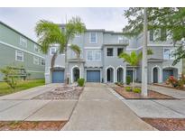 Charming townhomes boast inviting archways, blue garages, and lush landscaping, complemented by swaying palm trees at 618 Wheaton Trent Pl, Tampa, FL 33619