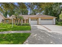 Charming single-story home featuring a three-car garage, lush lawn, and well-manicured landscaping at 6213 S Queensway Dr, Temple Terrace, FL 33617