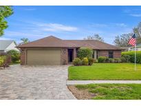 Charming single-story brick home featuring a two-car garage, manicured lawn, and beautiful paver driveway at 6352 Huntington Dr, Zephyrhills, FL 33542