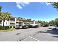 Condominium building with covered parking, palm trees, and a bright blue sky at 940 Virginia St # 304, Dunedin, FL 34698