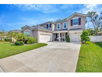Two-story home with a three-car garage, landscaped front yard, and a welcoming entryway at 12965 Satin Lily Dr, Riverview, FL 33579