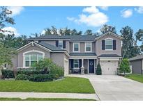 Beautiful two-story home featuring lush green lawn, manicured landscaping and three car garage at 12965 Satin Lily Dr, Riverview, FL 33579