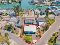 Aerial view of a single-story blue home in a waterfront community, offering a tranquil coastal lifestyle at 13098 Boca Ciega Ave, Madeira Beach, FL 33708
