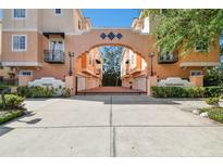 Gated entrance to complex featuring lush landscaping and attractive peach colored buildings at 3025 W Grovewood Ct # B, Tampa, FL 33629
