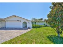 Charming single-story home featuring a well-maintained lawn, arched entryway and a brick-paved driveway at 5785 Bay Pines Lakes Blvd, St Petersburg, FL 33708