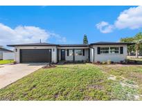 Charming single-story home with a well-maintained lawn and a driveway leading to an attached garage at 7327 Jasmine Blvd, Port Richey, FL 34668