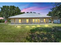 Inviting single-story home featuring a covered porch, white siding, and a metal roof, set on a large, grassy lot at 9019 S County Line Rd, Lithia, FL 33547