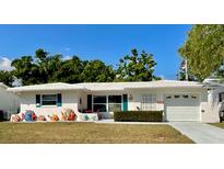 Charming single story home featuring tropical-themed decorations, manicured lawn, and a bright white exterior at 9308 45Th N St, Pinellas Park, FL 33782
