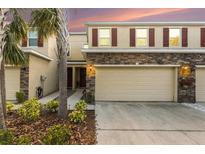 Inviting two-story townhome showcasing stone accents, a two-car garage, and lush landscaping at 13211 Canopy Creek Dr, Tampa, FL 33625