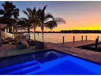 Inviting waterfront pool with modern lounge chairs at sunset reflecting off the pool and channel at 1493 Sea Gull S Dr, St Petersburg, FL 33707