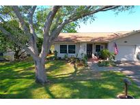 Charming home with a well-manicured front yard, mature tree, and an American flag proudly displayed at 2200 Marshall Dr, Dunedin, FL 34698