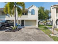 Inviting two-story home featuring an attached garage, manicured lawn, and a mature palm tree in the front yard at 2387 Hanover Dr # 2387, Dunedin, FL 34698