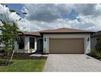 Charming single-story home with a two-car garage and paver driveway surrounded by a beautiful landscaped yard at 2760 Winding Creek Trl, North Port, FL 34289