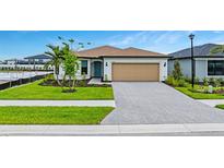Charming single-story home with a well-manicured lawn and a brick-paved driveway leading to the garage at 2760 Winding Creek Trl, North Port, FL 34289