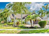 Beautiful single-story home featuring lush landscaping, palm trees, and brick driveway at 2966 Longbrooke Way, Clearwater, FL 33760