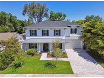 Beautiful two-story home boasts lush landscaping, a gray roof, black shutters, and a brick driveway at 3607 W Roland St, Tampa, FL 33609