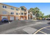 Exterior of condo building showing parking lot with palms and attached garages under a blue sky at 10764 70Th Ave # 1205, Seminole, FL 33772