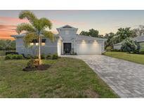 Beautiful single-story home with a manicured lawn, mature landscaping, and a brick paved driveway at 12546 Wildebeest Way, Spring Hill, FL 34610