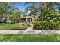 Charming home showcasing a lush landscaped front yard with a brick walkway and mature trees at 250 Aberdeen St, Dunedin, FL 34698
