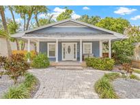Charming home featuring a landscaped yard, brick walkway, and covered front porch at 7708 N Arden Ave, Tampa, FL 33604