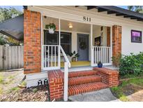 Charming front porch with brick stairs and columns, with hanging plants and a colorful rug at 811 E Flora St, Tampa, FL 33604