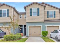 Charming townhome with tan siding, a one car garage, well-kept landscaping, and blue shutters at 9213 Hillcroft Dr, Riverview, FL 33578
