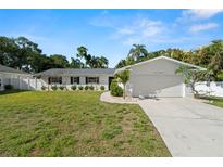 Charming single-story home with a two-car garage, well-maintained lawn, and tropical landscaping in a sunny, inviting setting at 1698 Eden Ct, Clearwater, FL 33756