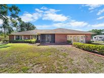 Charming brick home featuring a large front yard, a screened entryway, and well-maintained landscaping at 1702 Miller S Rd, Valrico, FL 33594