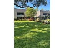Exterior view of a well-maintained two-story building with lush green lawn and beautiful landscaping at 36750 Us 19 N # 5-111, Palm Harbor, FL 34684