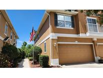 Charming townhome with an attached garage, neat landscaping, and American flag waving out front at 7530 Red Mill Cir, New Port Richey, FL 34653