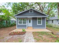 Charming grey home featuring a white door, white trim, and well-maintained landscaping at 8008 N Alaska St, Tampa, FL 33604