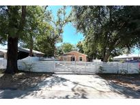 Charming home featuring a white fence and mature trees enhancing its curb appeal on a sunny day at 8516 N Dixon Ave, Tampa, FL 33604