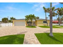 Charming yellow home with well-manicured lawn, paver driveway, white fence, and tropical palm tree landscaping at 8801 Gulf Blvd, St Petersburg, FL 33706