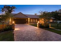 Charming home exterior featuring a brick driveway, stone accents, and professionally manicured landscaping with attractive outdoor lighting at 113 Garland Cir, Palm Harbor, FL 34683