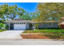 Charming one-story home featuring a well-maintained lawn, a two-car garage, and mature trees offering shade at 12536 116Th St, Largo, FL 33778
