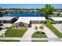 Beautiful waterfront home with manicured lawn, circular driveway, and lush landscaping offering picturesque views at 13797 Pinecrest Dr, Largo, FL 33774