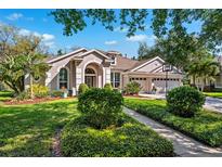 Charming stucco home with a landscaped front yard, arched entryway, three-car garage, and well-manicured lawn at 15930 Sorawater Dr, Lithia, FL 33547