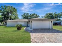 Charming single-story home featuring a well-manicured lawn and a brick-paved driveway leading to an attached two-car garage at 1968 Rolling Green Cir, Sarasota, FL 34240